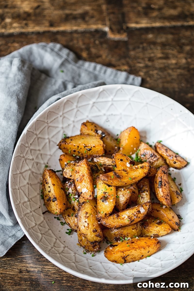 A bowl filled with perfectly roasted Chipotle Mayo Potato Wedges, garnished with fresh chives, viewed from directly above.