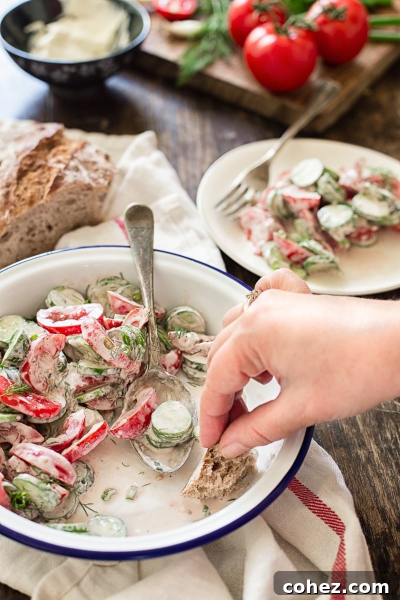 Refreshing Tomato Cucumber Crunch 6 A beautifully presented serving bowl of creamy tomato and cucumber salad, garnished generously with fresh dill