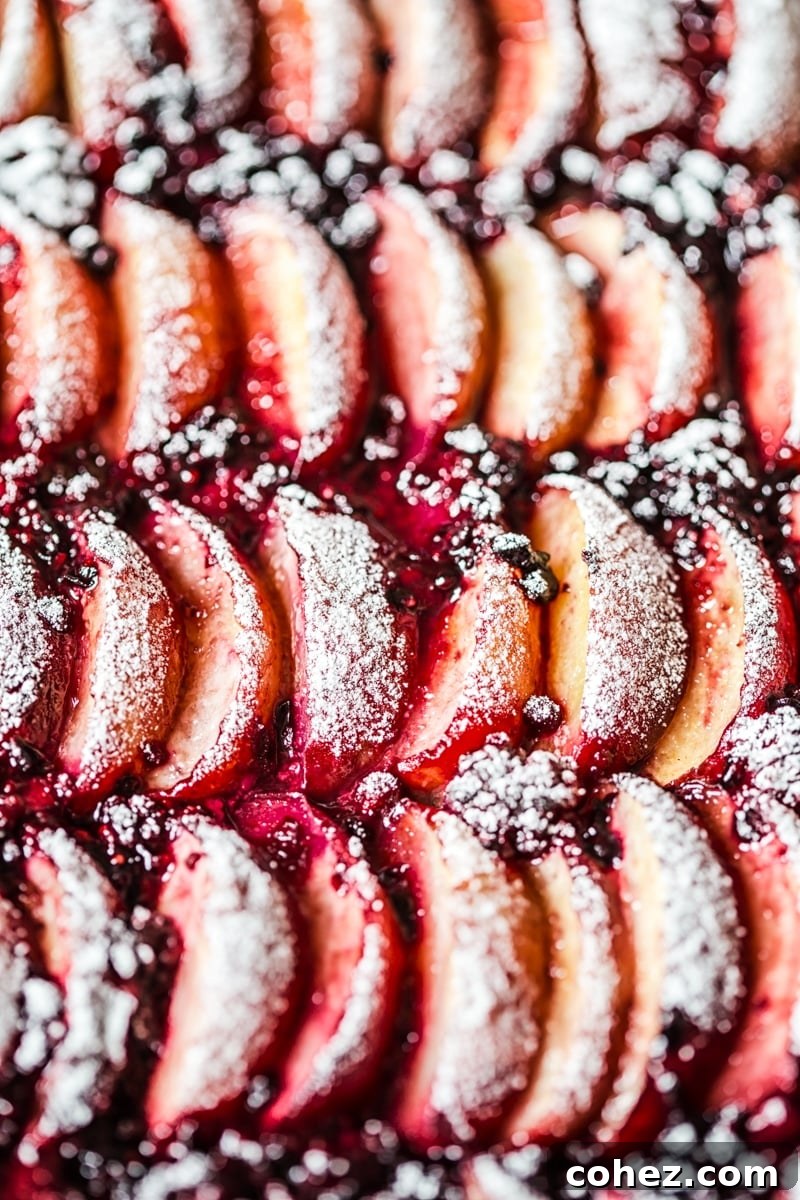 Close up of perfectly baked peaches and blackberries on a golden tart