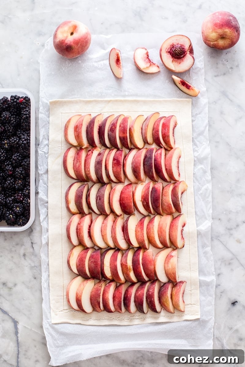Sliced peaches arranged neatly on puff pastry before baking