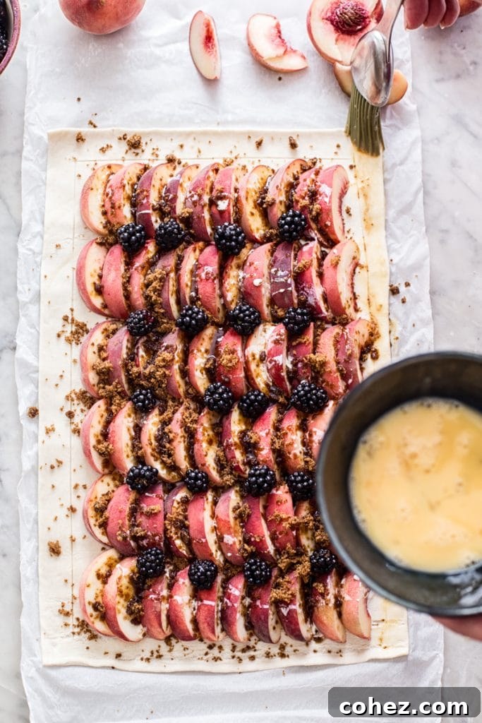 Unbaked peach and blackberry tart with a bowl of beaten egg for brushing