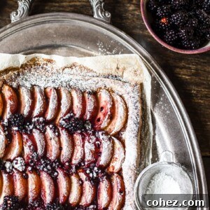 Corner of the tart next to icing sugar and blackberries