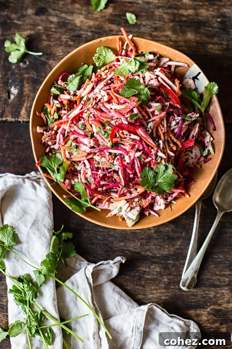 Top-down view of a colorful bowl of rainbow slaw garnished with sesame seeds.