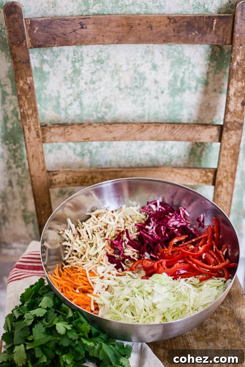 A bowl filled with freshly shredded vegetables, ready for dressing, on a rustic wooden surface.
