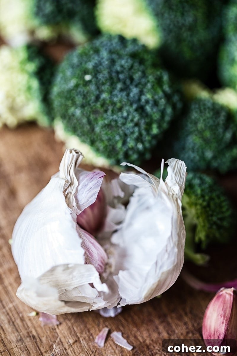Sun-Kissed Tomato & Parmesan Roasted Broccoli 5 A head of fresh broccoli and garlic bulbs on a rustic wooden surface, ready for preparation