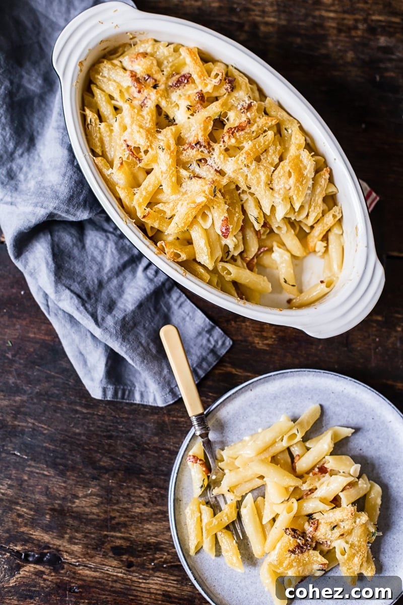 Top-down view of a single serving of Brie and Bacon Macaroni and Cheese on a white plate, garnished with fresh herbs.