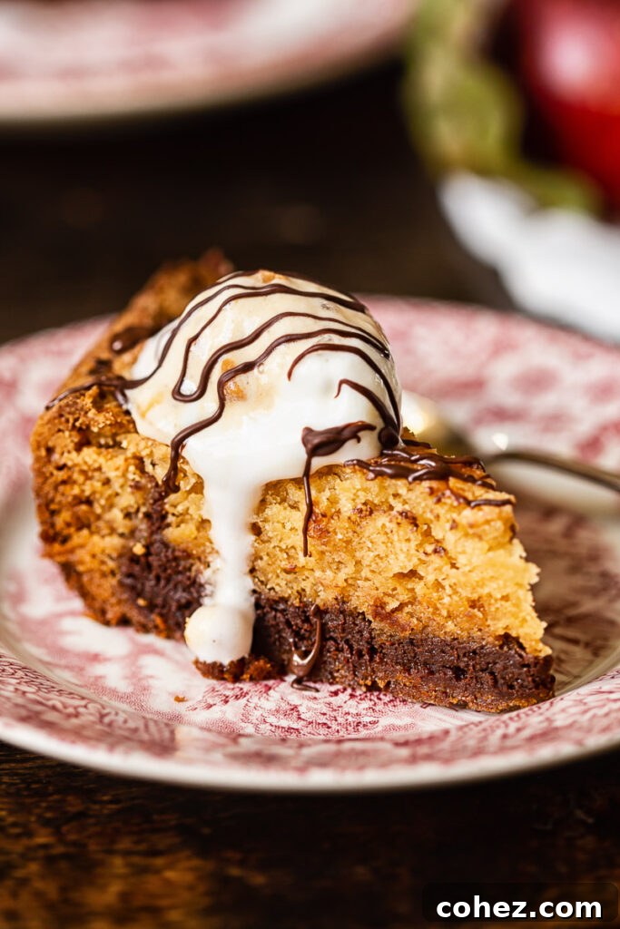 A single chocolate butterscotch cookie bar on a plate, beautifully topped with a scoop of melting vanilla ice cream.