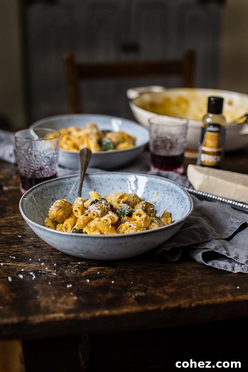 Side shot of a bowl of Sausage Meatball and Pumpkin Pasta with a fork, showing the creamy sauce and tender meatballs