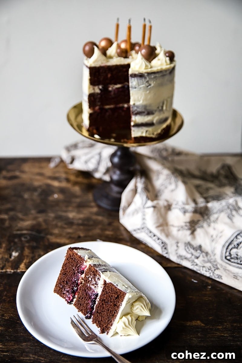 Black and white cake on a stand with slice removed onto a plate