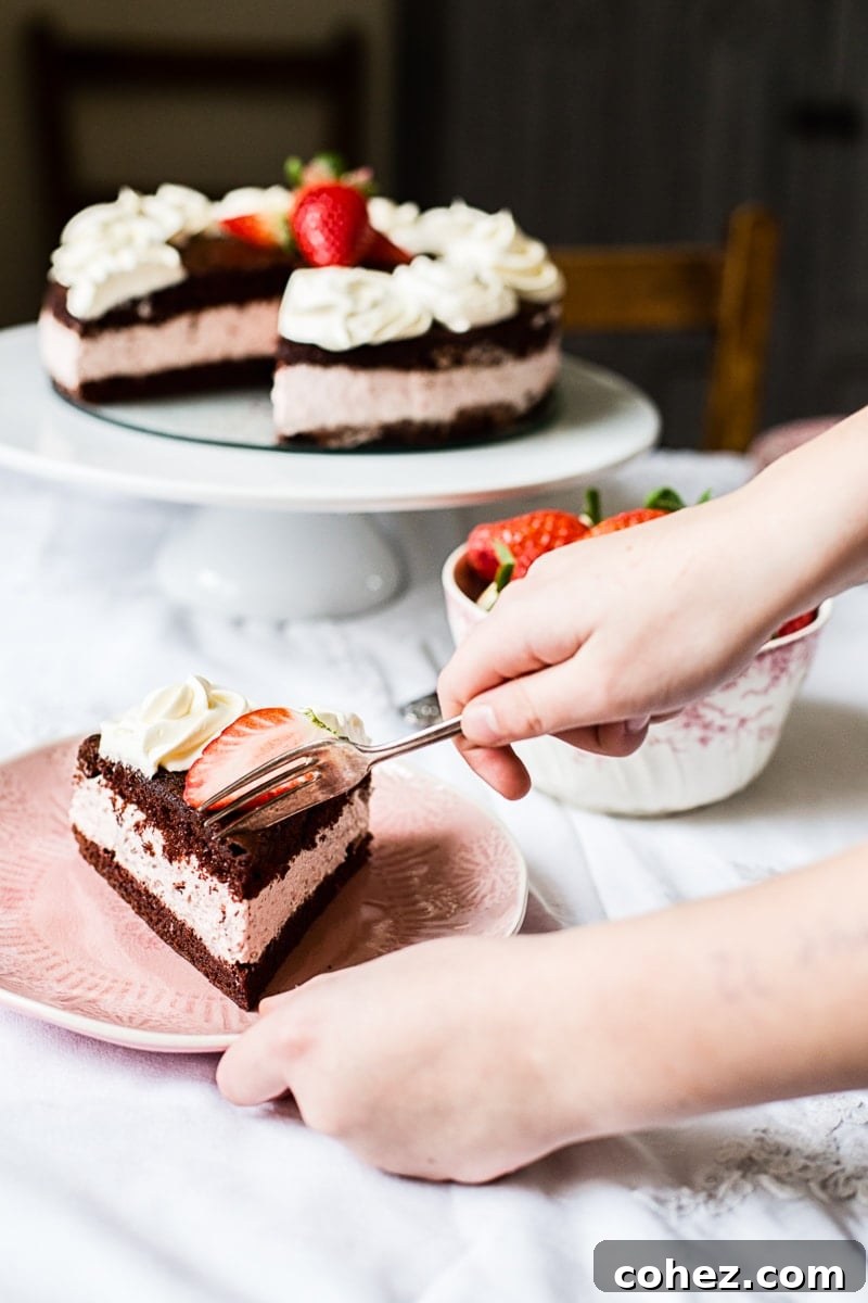 A hand with a fork taking a piece of the delightful Chocolate Strawberry Mousse Cake.
