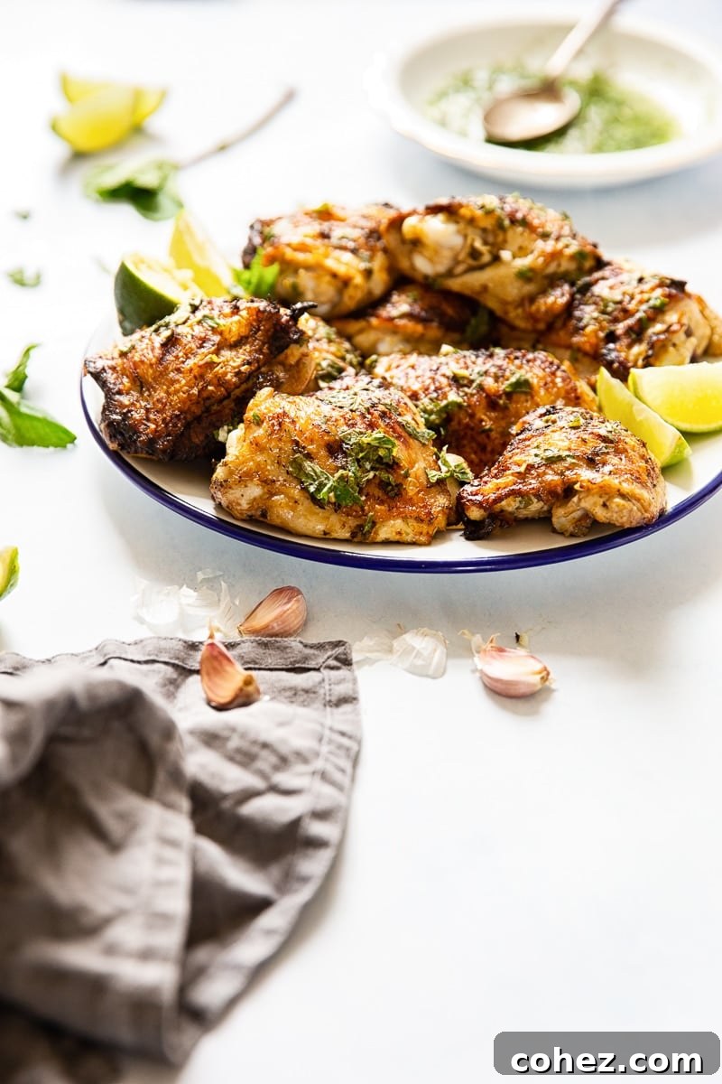Plate of the Mojito Grilled Chicken Thighs against a white background with lime and mint garnishes