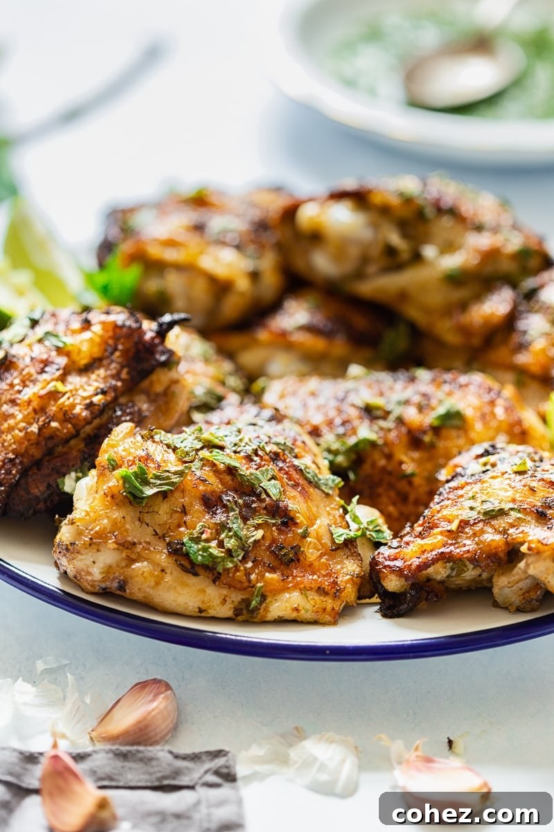 Close-up of a grilled chicken thigh on a white plate