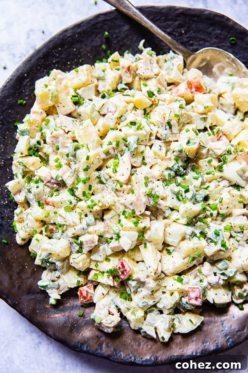 Top-down view of a generously portioned Russian salad Olivier, garnished with fresh dill.