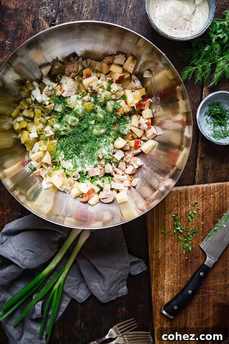 Undressed potato salad ingredients, diced and ready for mixing, in a sleek stainless steel bowl.