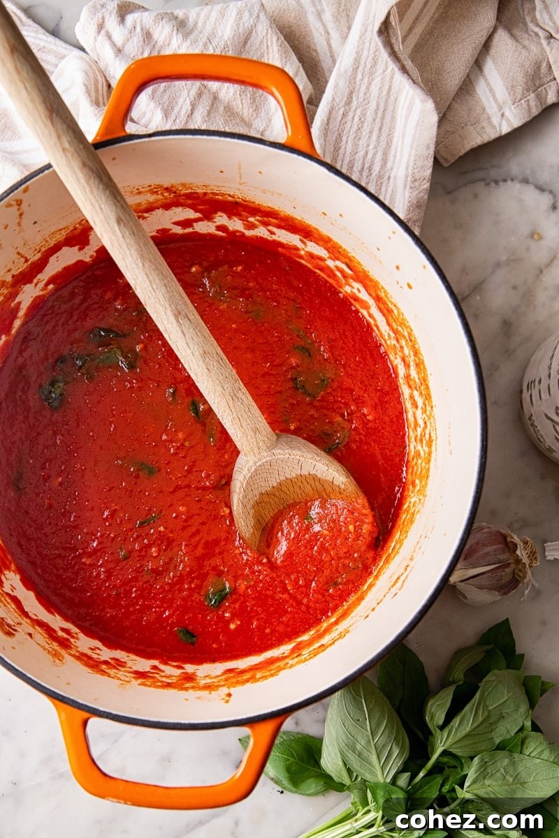 A large pot brimming with rich spaghetti sauce, accompanied by a wooden spoon resting inside, ready for serving