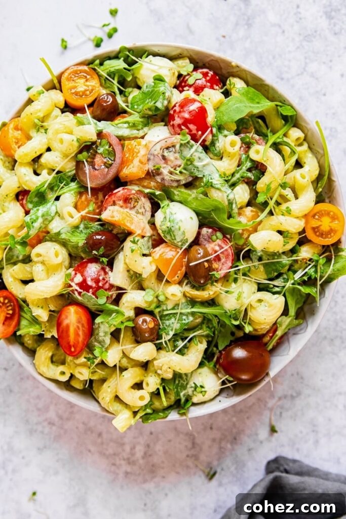 Close-up, top-down view of creamy Green Goddess Pasta Salad with fresh ingredients