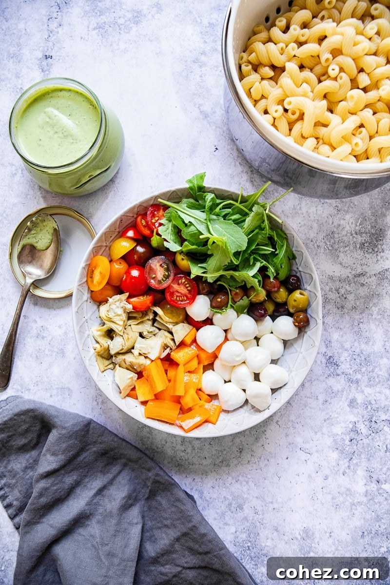 Assortment of fresh salad ingredients including pasta, tomatoes, mozzarella, and olives