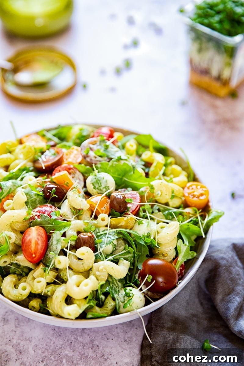 Overhead view of a large bowl of Green Goddess Pasta Salad, garnished with fresh herbs