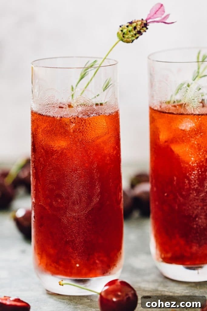 Two glasses of vibrant cherry long island iced tea garnished with fresh cherries.