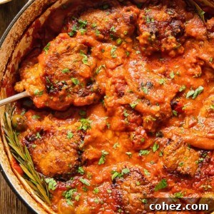 Top-down view of Chicken Cacciatore in a pan, a hearty Italian dish with rich tomato sauce and crispy chicken pieces.