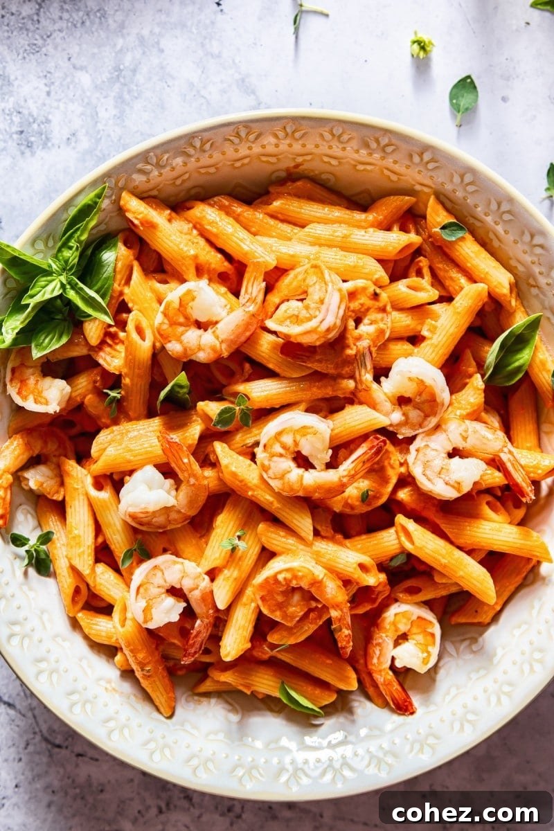 Close-up aerial view of a bowl of shrimp penne alla vodka, garnished with fresh parsley