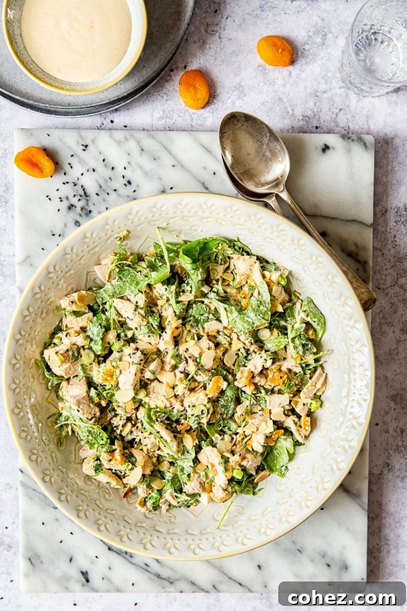 Perfect Coronation Chicken 3 Top-down view of Coronation Chicken Salad in a bowl, garnished with apricots and spoons