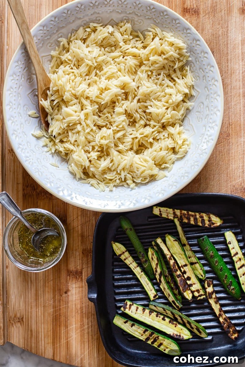 Close-up of Greek Orzo Salad ingredients, highlighting the grilled zucchini and feta cheese