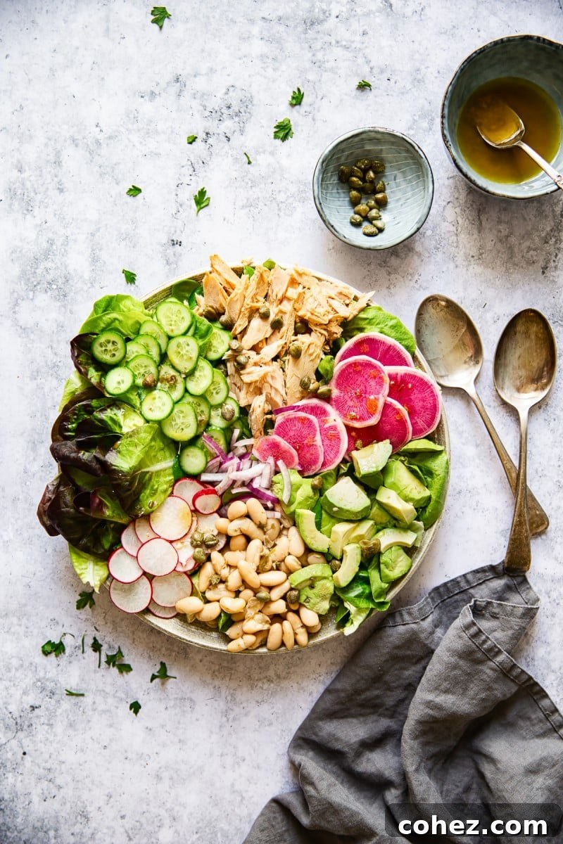 Top down view of tuna salad with bowls of capers and dressing