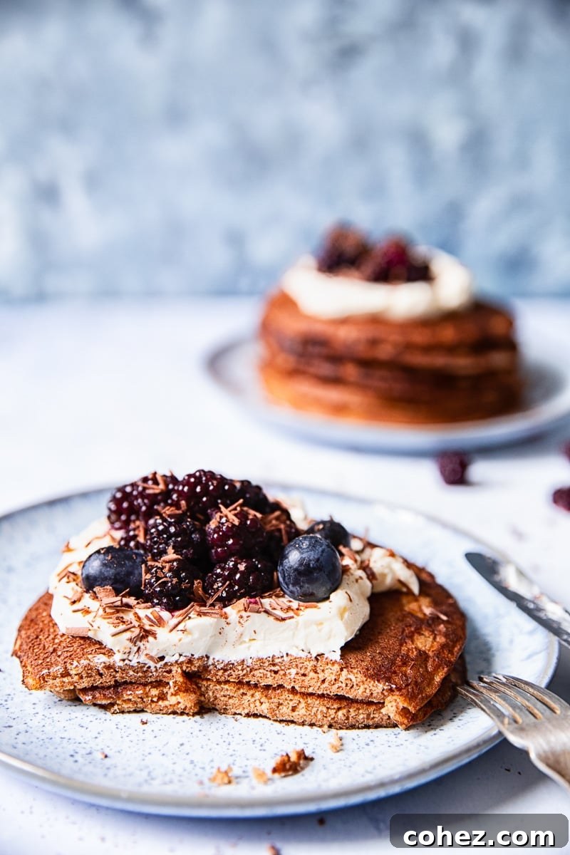 two pancakes on a light blue plate with a portion cut off, another plate with pancakes in the background