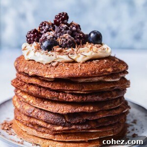 a stack of buckwheat pancakes, topped with whipped cream and berries