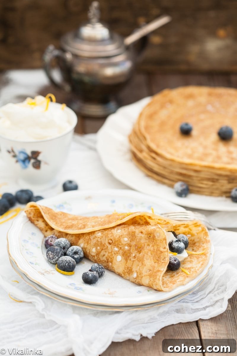 Golden-brown cheese blintzes piled high, garnished with fresh blueberries and a dusting of powdered sugar, ready for a special breakfast or brunch.