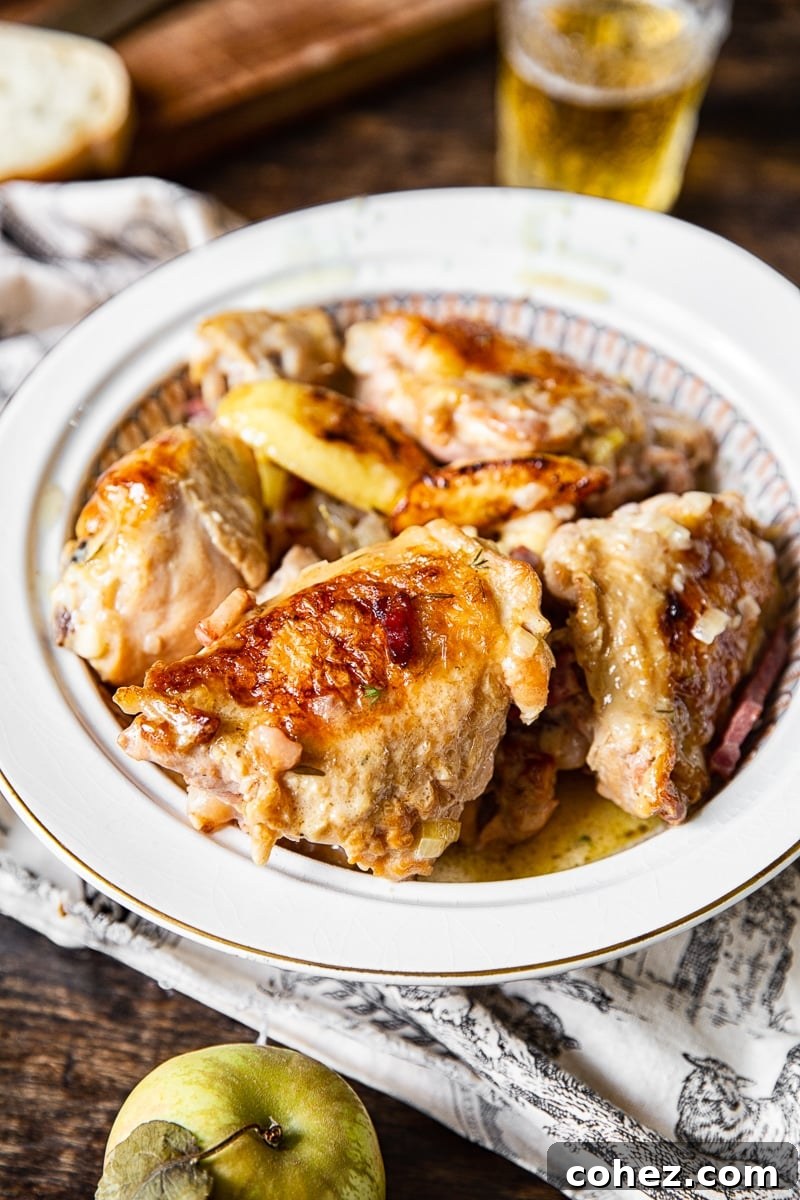 Normandy Cream Chicken Bake 6 braised chicken thighs in serving dish, garnished with fresh herbs and apple slices