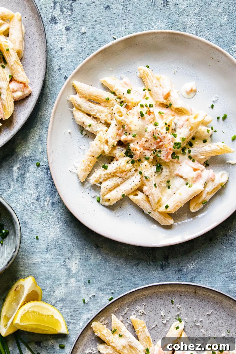 Decadent Smoked Salmon Pasta 4 Overhead shot of creamy pasta with smoked salmon and herbs on a white plate.