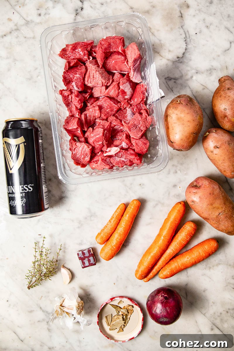 Fresh ingredients laid out for Irish Beef Stew, including beef, vegetables, and a can of Guinness.