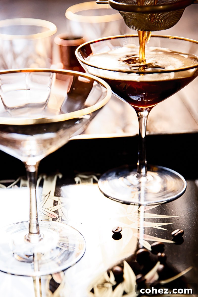 Espresso Martinis being poured through a fine mesh strainer into chilled glasses