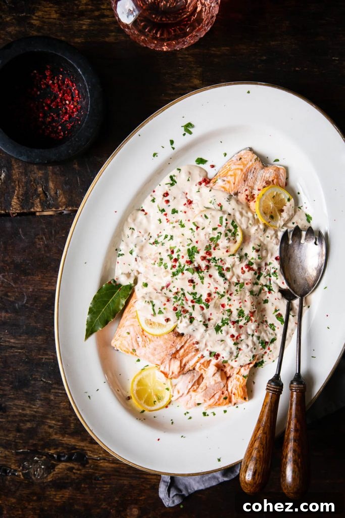 A festive serving tray showcasing a whole baked salmon adorned with rosé cream sauce, ready for a holiday feast.
