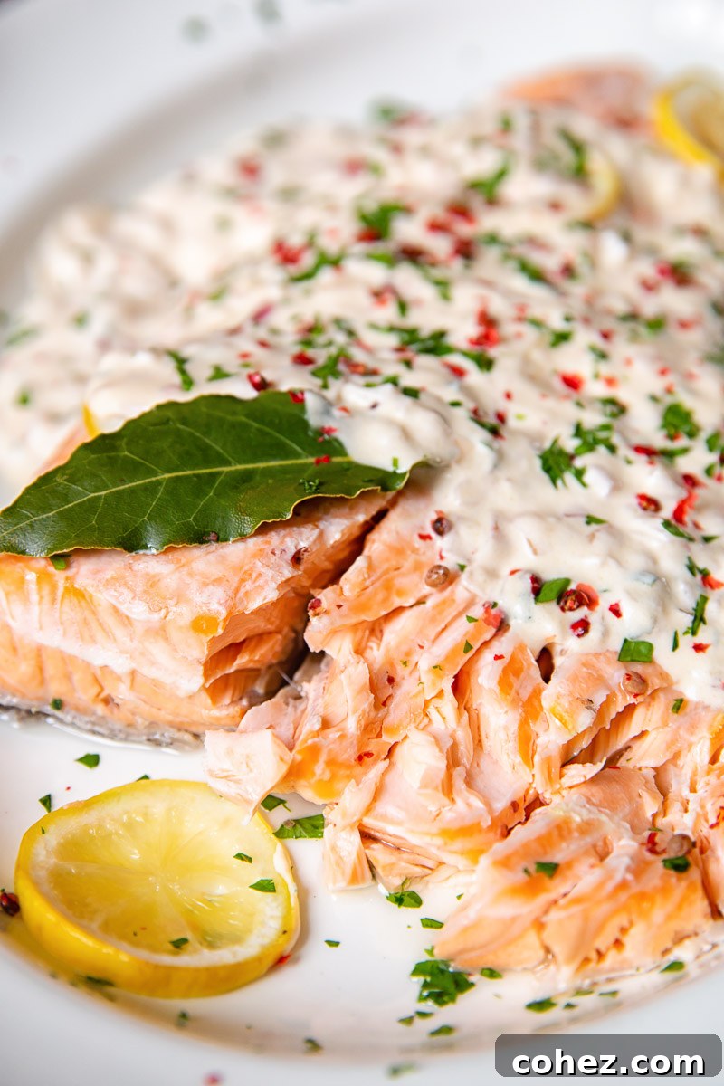 A close-up shot of baked salmon covered in a glistening rosé cream sauce, ready to be served.