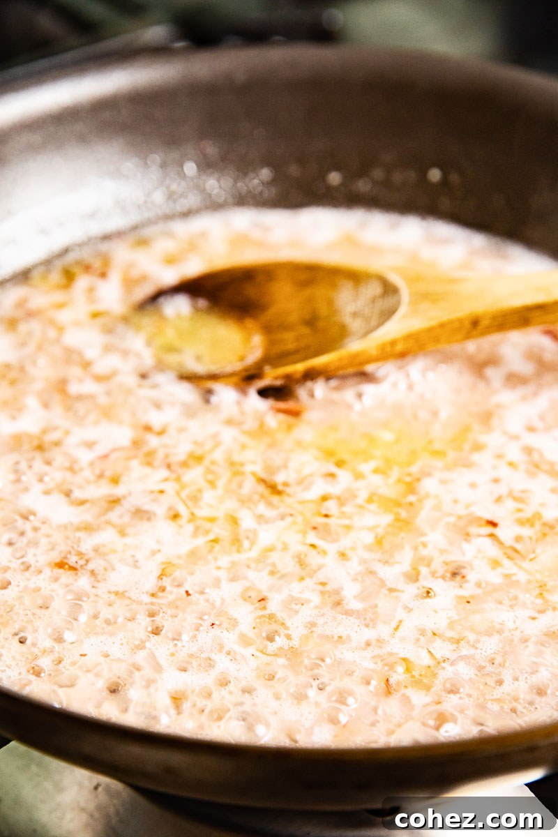 A frying pan containing the rich, creamy rosé sauce, with a wooden spoon resting inside.