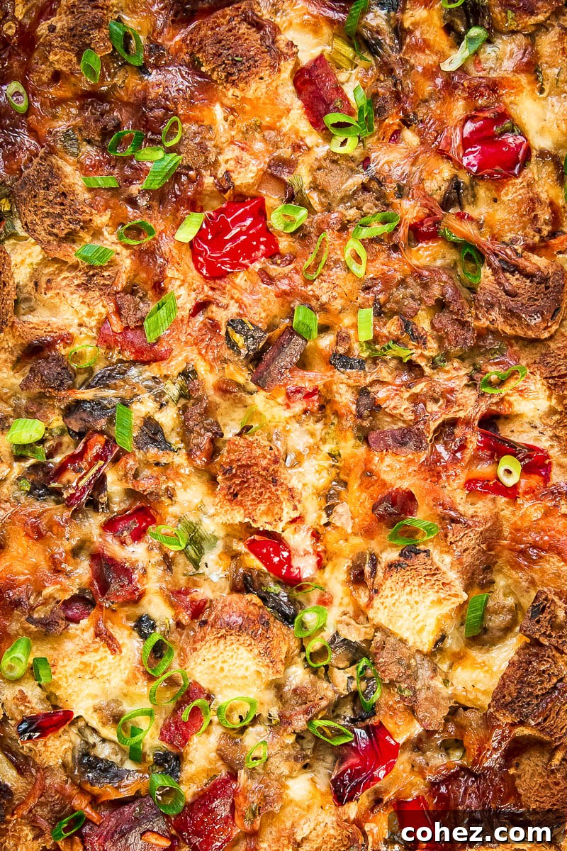 Morning-Ready Sausage and Chorizo Egg Bake 3 Close-up shot of the baked breakfast casserole, showing the golden-brown top, bubbling melted cheese, and clearly visible pieces of sausage, chorizo, and colorful vegetables.