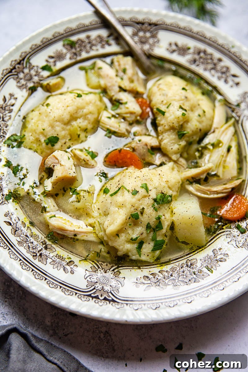 Close-up shot of fluffy buttermilk dumplings simmering in a rich chicken broth with diced vegetables.