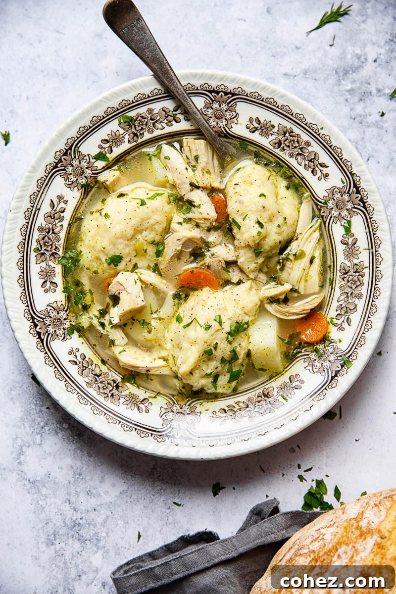 A close-up of a serving of chicken and dumpling soup, highlighting the tender chicken pieces, vibrant vegetables, and perfectly cooked dumplings.