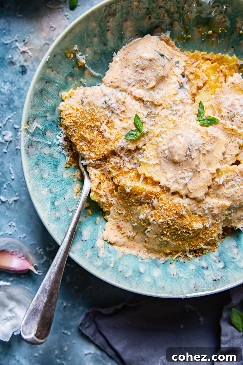 Creamy sun-dried tomato ravioli sauce in a skillet with fresh basil