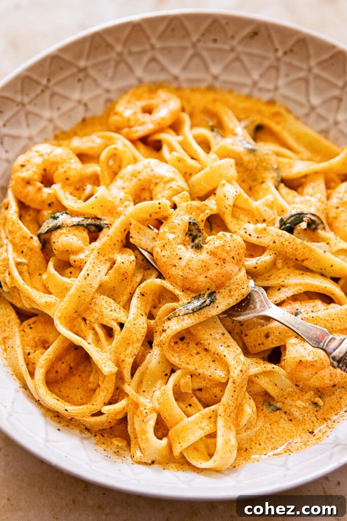 Prawn pasta in creamy tomato sauce in brown bowl, garnished with fresh basil.