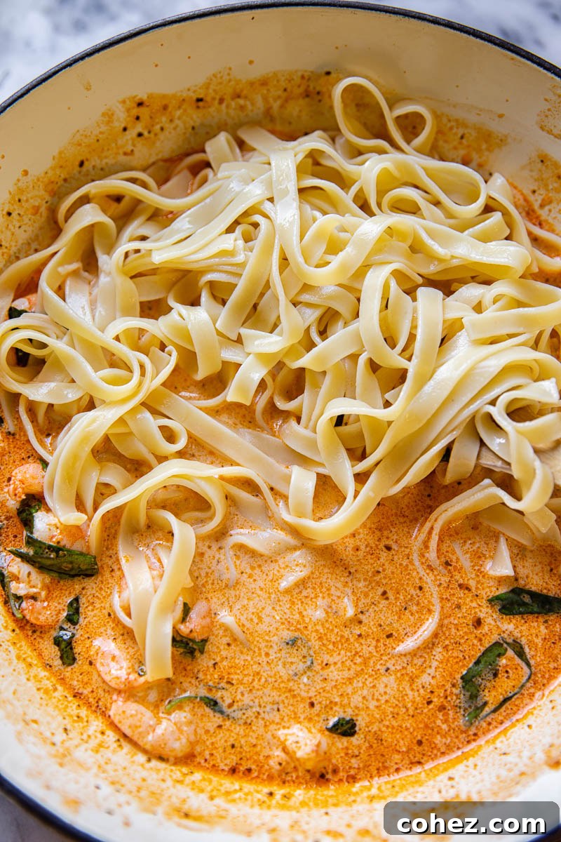 Linguine in creamy sun-dried tomato sauce with shrimp and fresh basil, served in a pan.