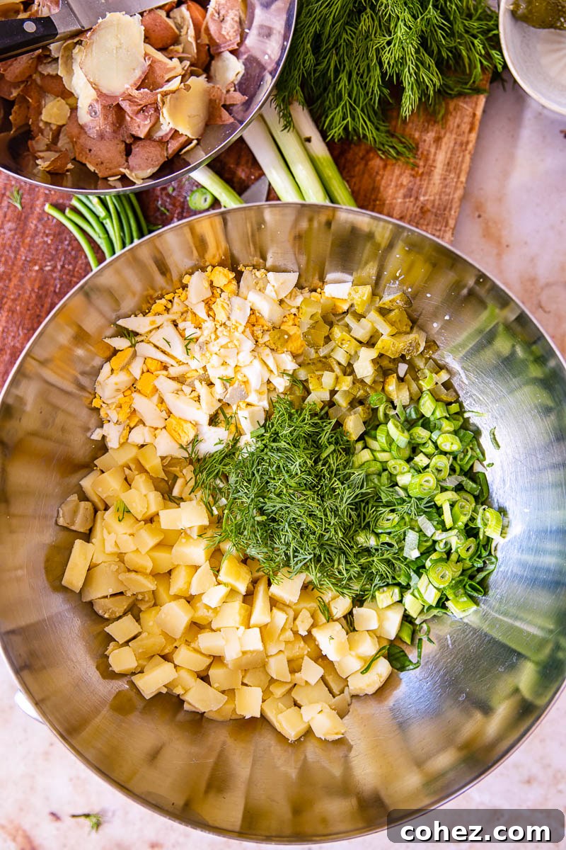 Fresh ingredients laid out for dill potato salad, including waxy potatoes, hard-boiled eggs, green onions, and fresh dill.