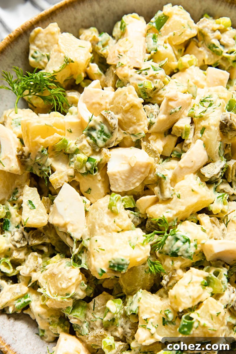 Close-up of creamy dill potato salad, showcasing the texture and fresh herbs.