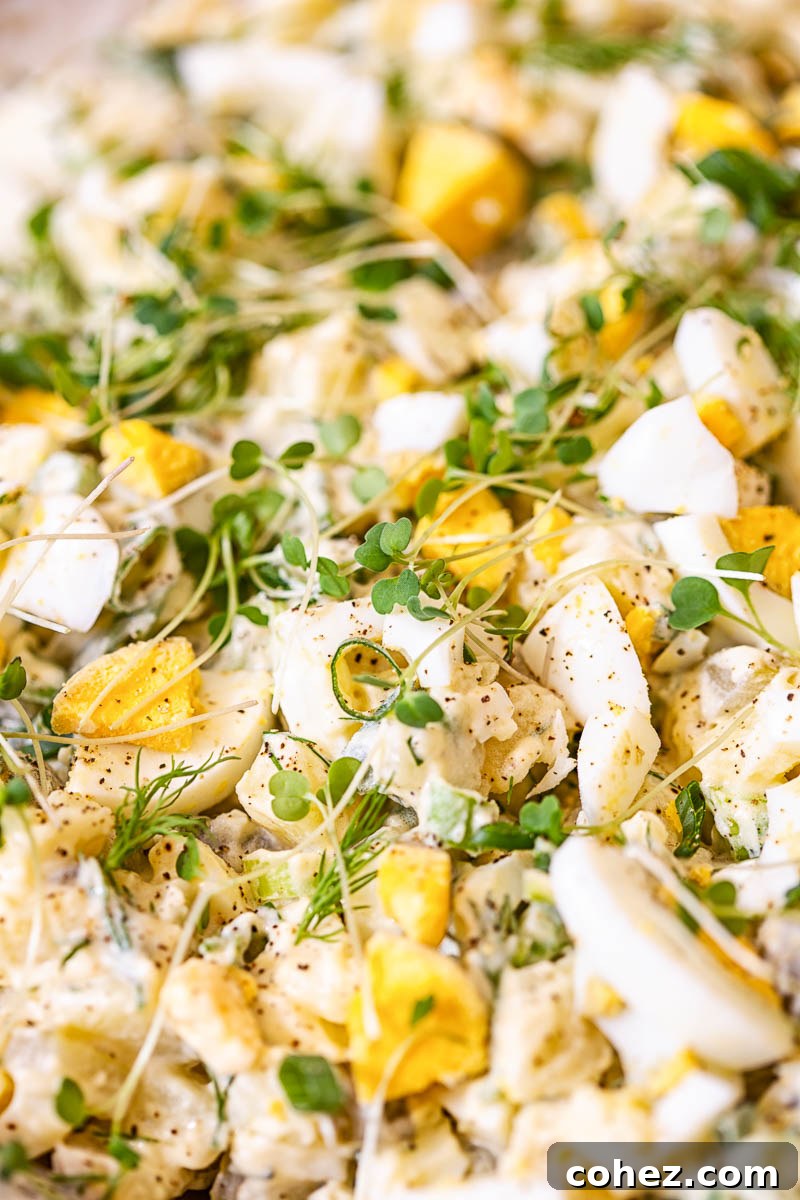 Closeup shot of dill potato salad, highlighting microgreens and the creamy texture.