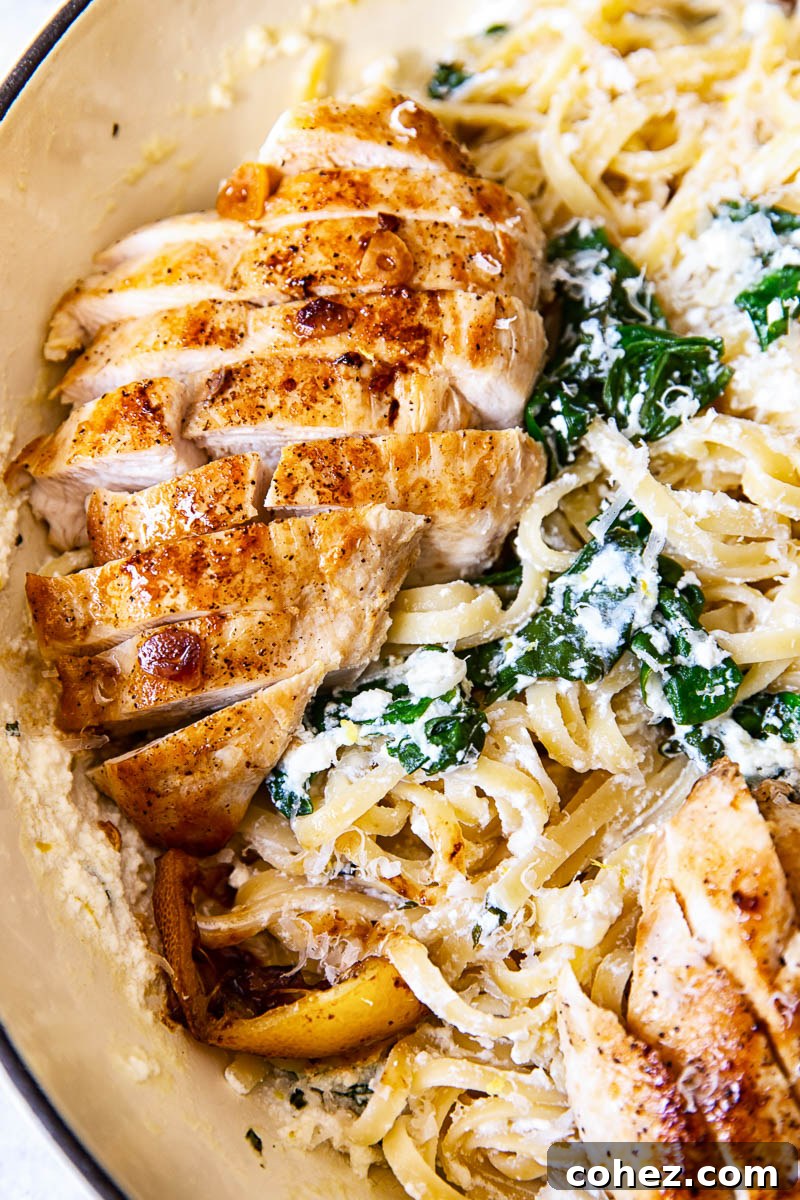 Sliced lemon butter chicken breasts on top of spinach ricotta pasta