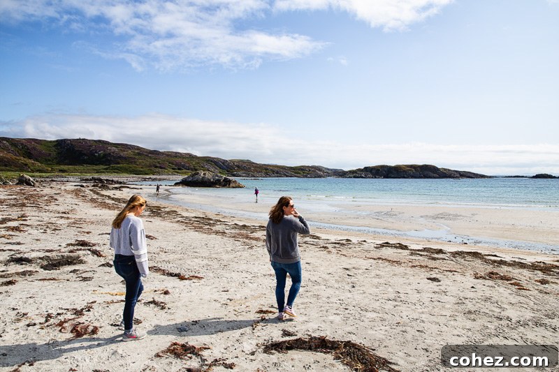 Isle of Mull Scotland's Untamed Beauty 3 A stunning Scottish beach on the Isle of Mull, featuring pristine golden sands leading to clear turquoise waters, with rugged coastal cliffs framing the scene under a dramatic sky.