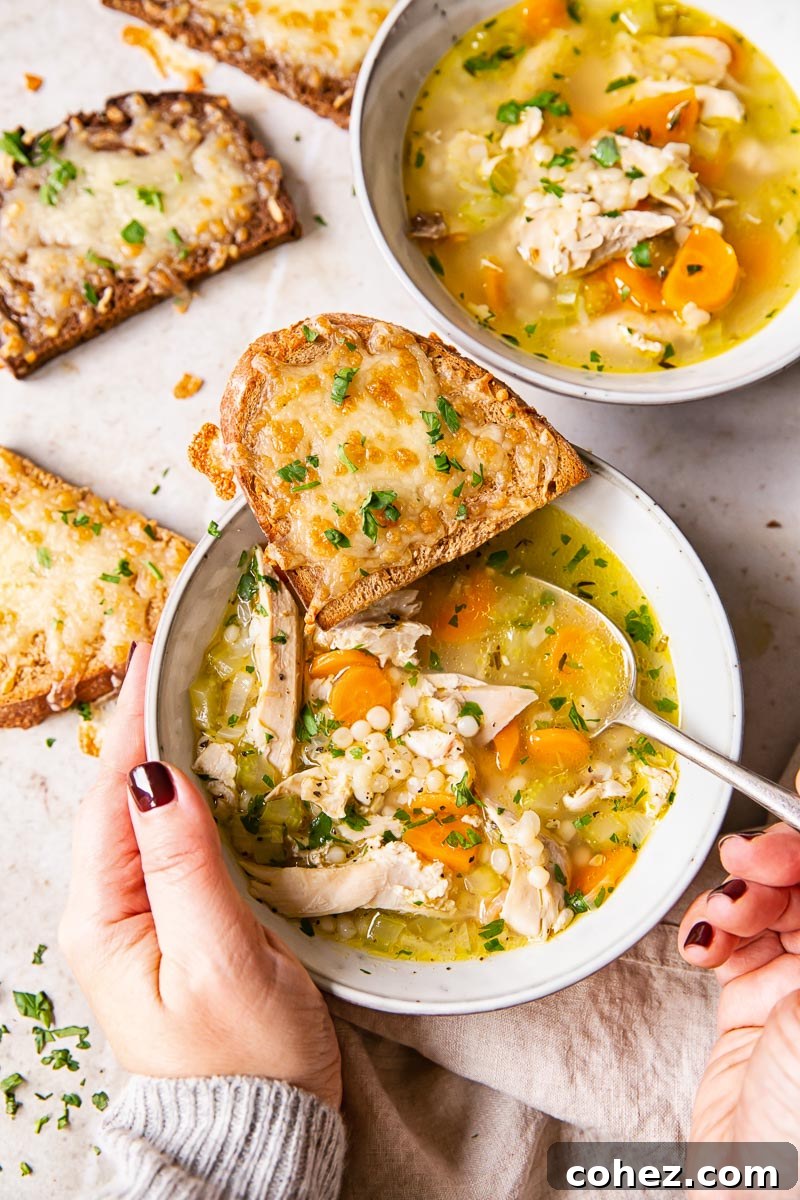 Hands holding a comforting bowl of Leftover Turkey Soup, with cheesy rye toast on the side, highlighting a perfect pairing.